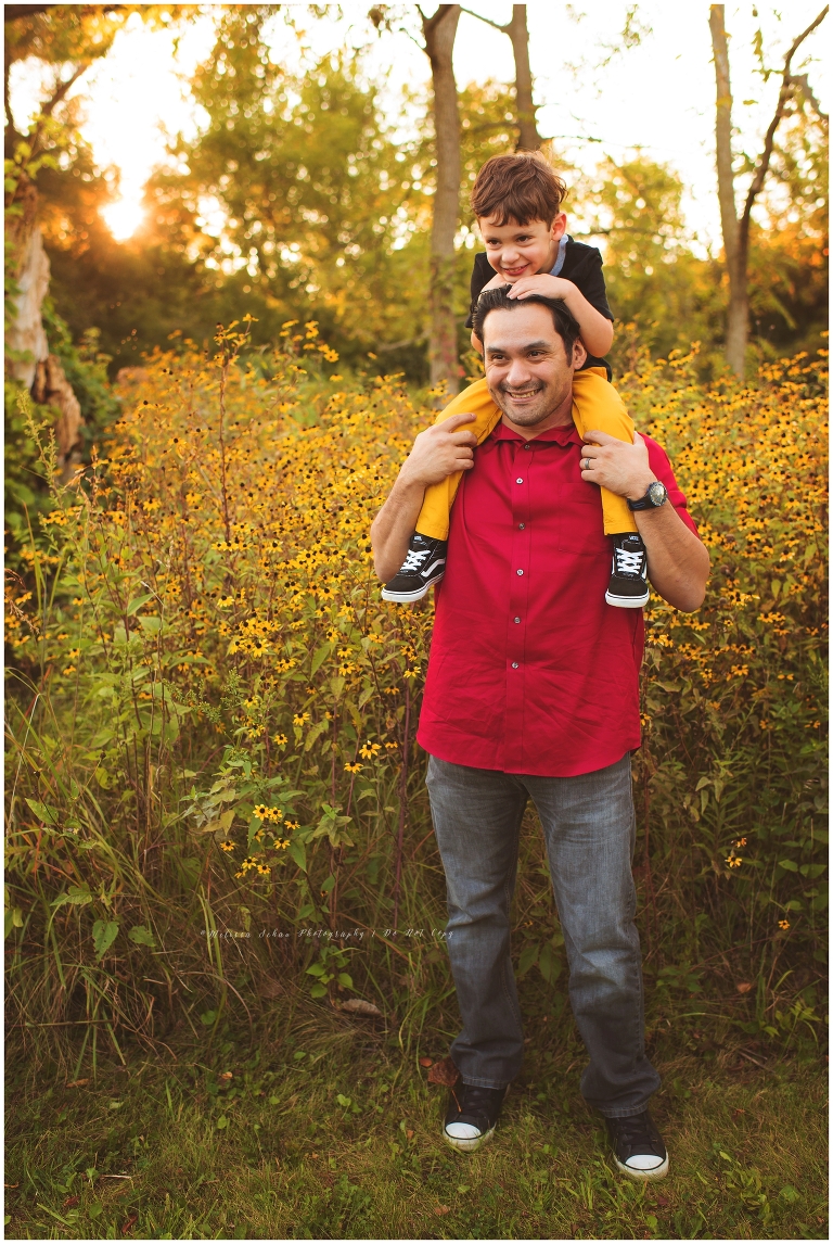 Boy on dad's shoulders for outdoor photography session in flowers
