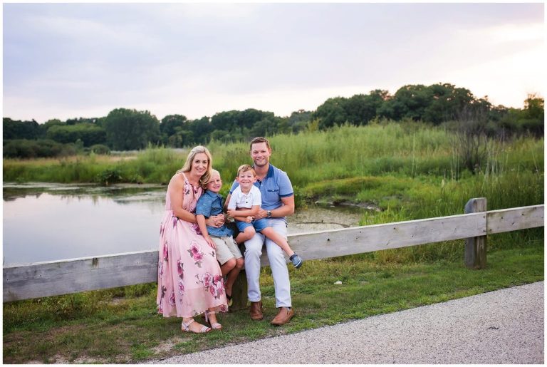 family sitting on wooden guardrail portrait